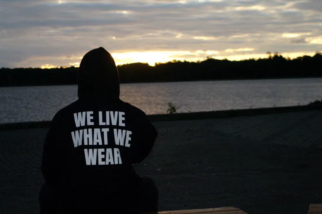 Plecy z napisem WE LIVE WHAT WE WEAR na tle zachodu słońca