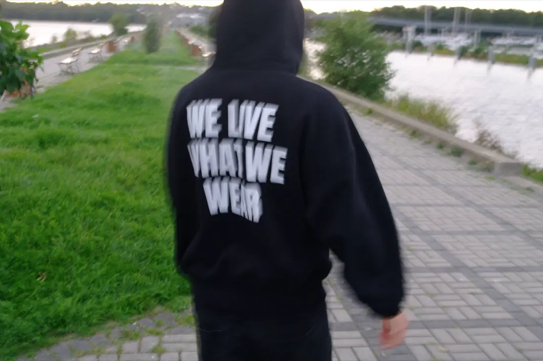 Osoba w bluzie idzie promenadą nad wodą